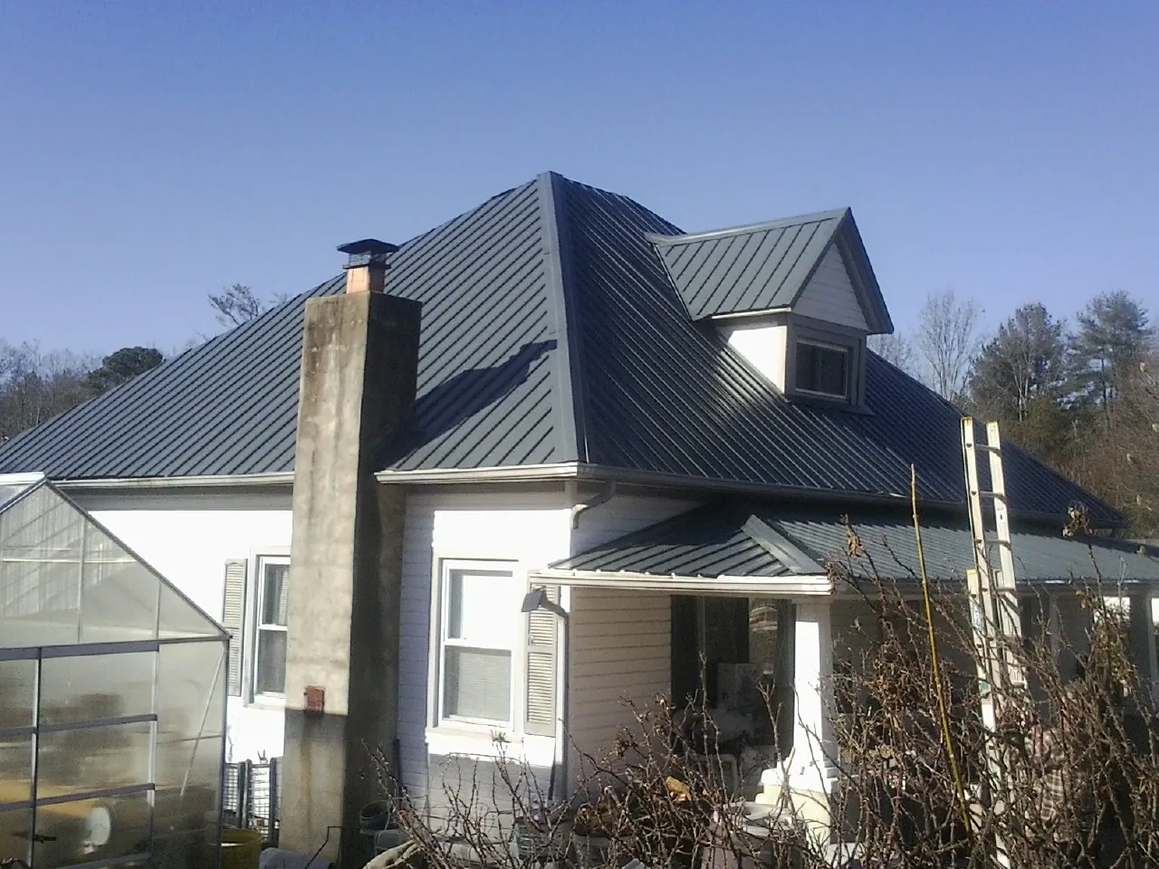 Dark blue standing seam metal roof on a white farmhouse with dormer — Slate & Tile Roof Repair by Roofing Brothers in Catlett