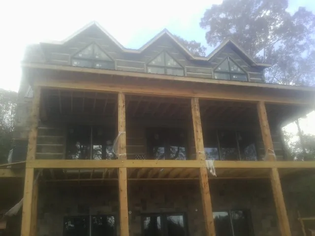 Dormers and porch framing on a large log home under construction — Roof Coating work by our crew in Catlett