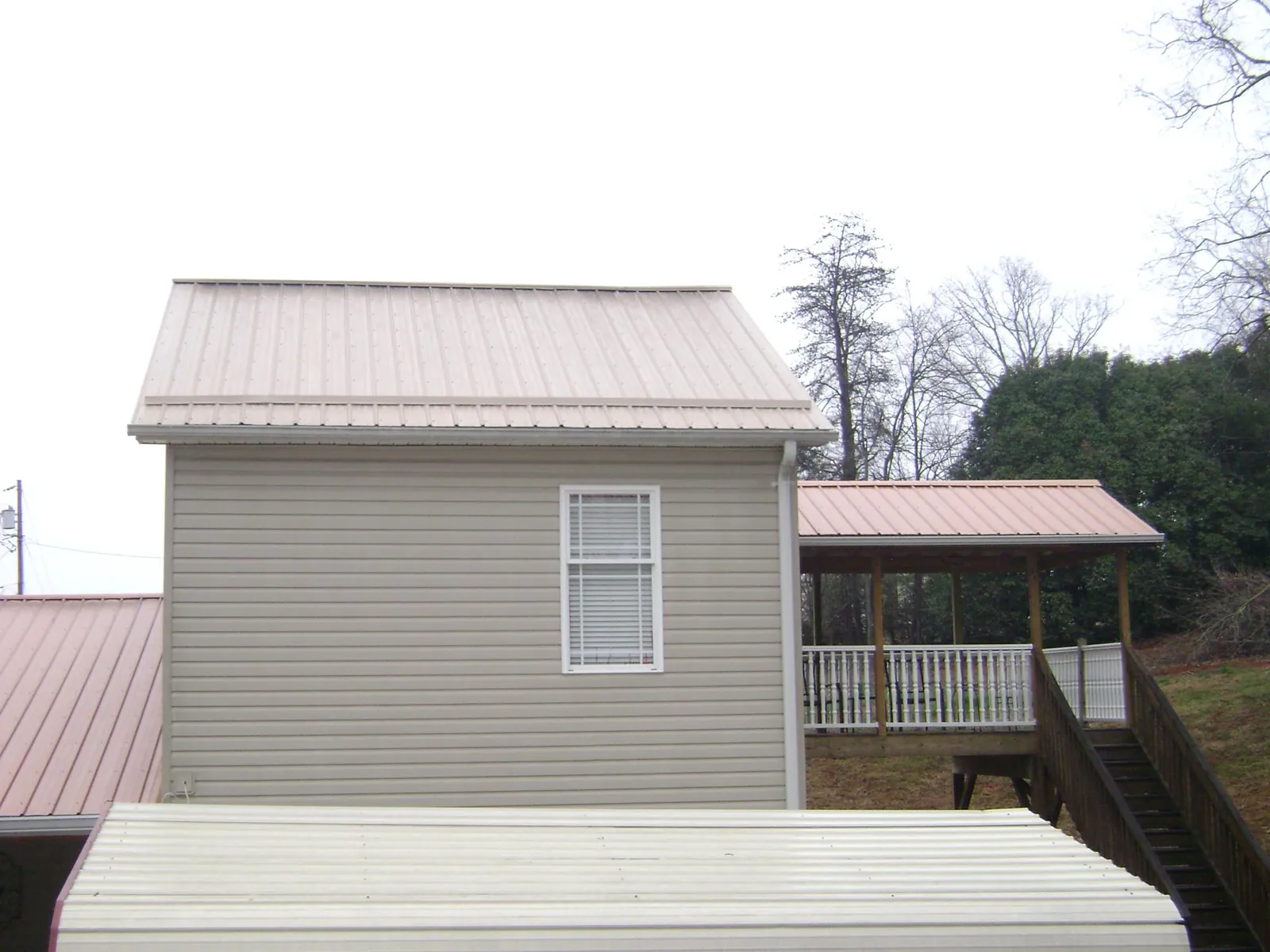 Tan metal roofs on a two story addition and attached porch, from a Roof Replacement job in Catlett