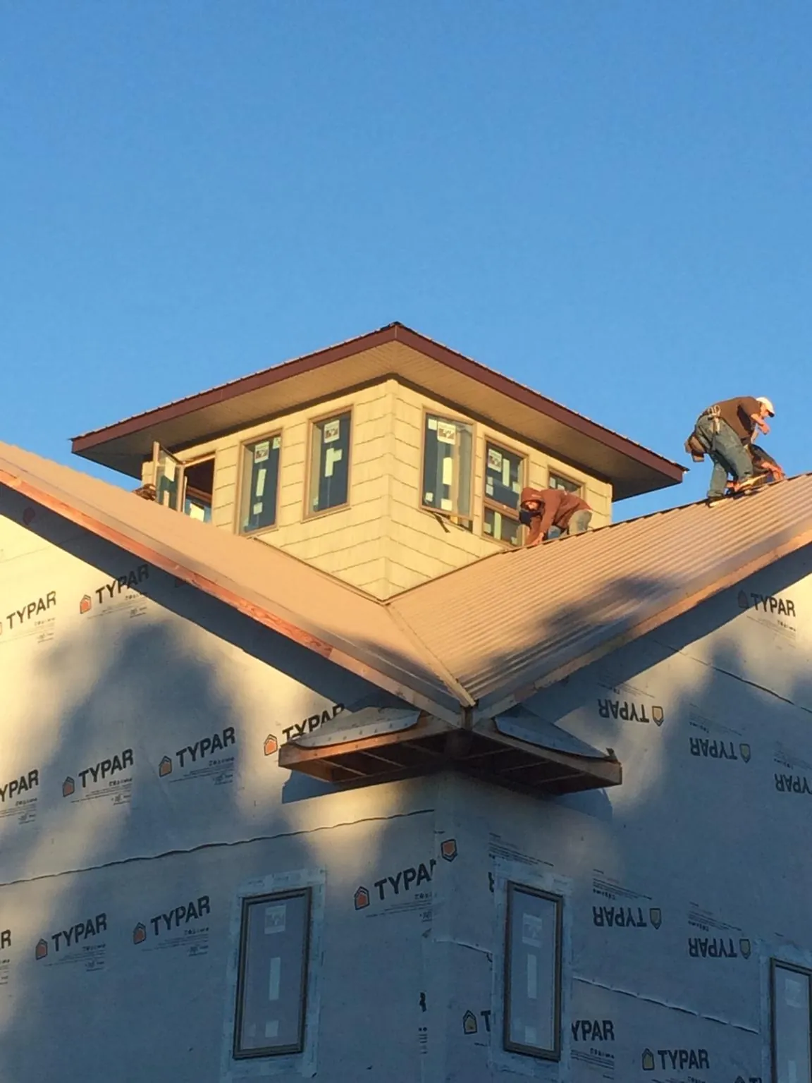Roofers working around a rooftop cupola on a new metal roof at sunset — Roof Waterproofing in Catlett by Roofing Brothers